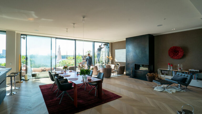 Modernes Wohnzimmer mit großen Fenstern und Essbereich.