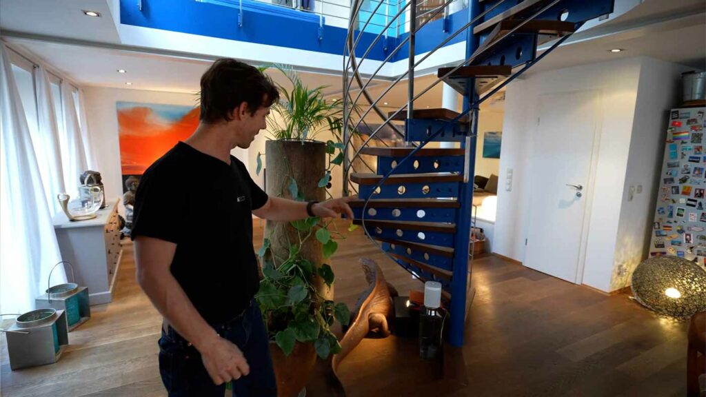 Mann in modernem Wohnzimmer mit Wendeltreppe.